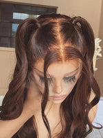 A close-up of a dark brown wig with a middle part, styled in two half-up pigtails with loose curls by WigOutlets