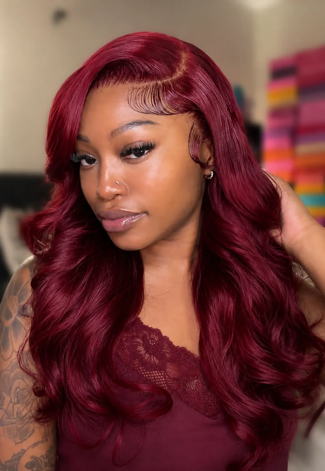 A woman with long, wavy, burgundy human hair wig from WigOutlets